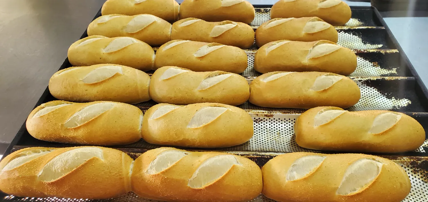 Bandeja de pães franceses assados, alinhados e dourados